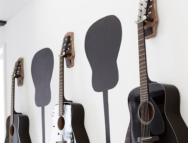 Three wooden guitar mounts holding acoustic guitars
