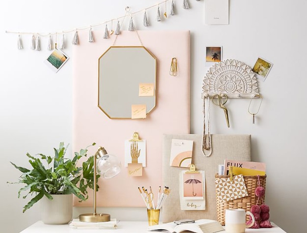 Pink pinboard with gold mirror above desk