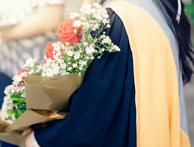 Graduate holding bouquet of flowers
