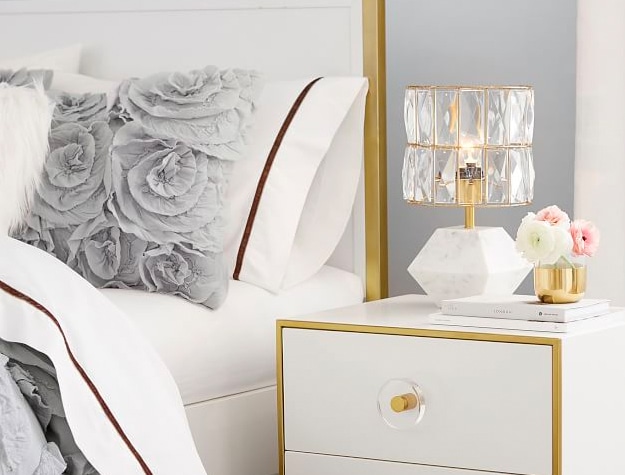 Monique Lhuillier Marble Gem table lamp on bedside table next to stack of books with small flowers.