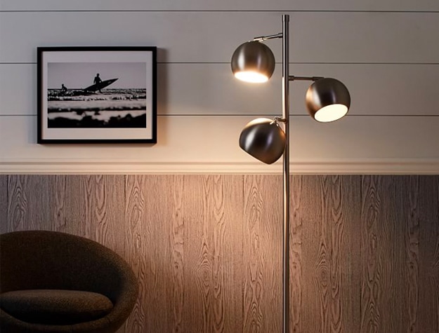 Brushed Nickel Metallic Spotlight Floor Lamp next to a chair and framed photo of surfers.