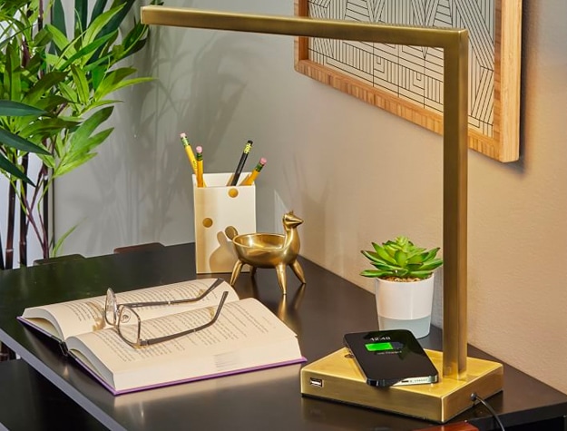 Overhead Greene Table Lamp with phone charging on its base net to an open book with glasses and office supplies.