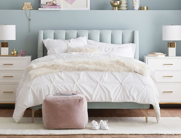Light blue velvet upholstered Avalon bed styled with a white comforter and white modern nightstands.