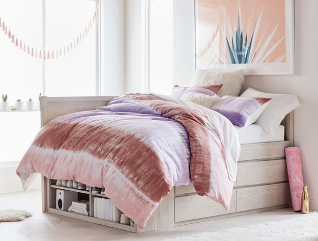 Full-sized Costa corner captain’s bed in weathered white wood styled with a tie-dye comforter.