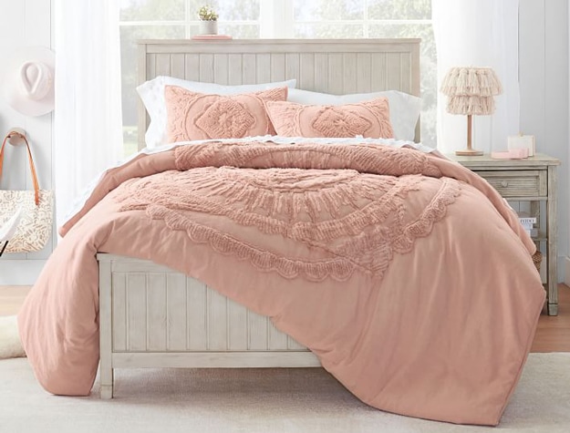 Beadboard bed in weathered white styled with a dusty pink comforter and pillows.