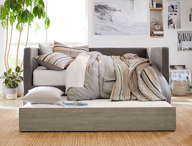 Gray Bailey daybed with trundle styled in a room with plants and a hanging picture of an ocean.