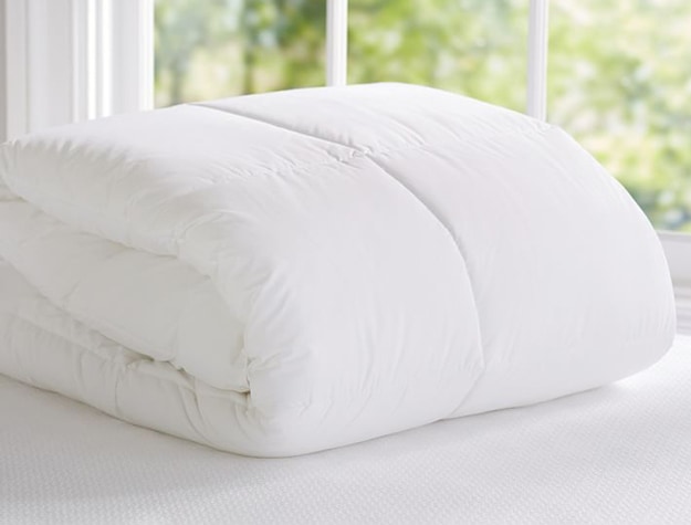 A fluffy white Essential Duvet Insert folded neatly on a bed.