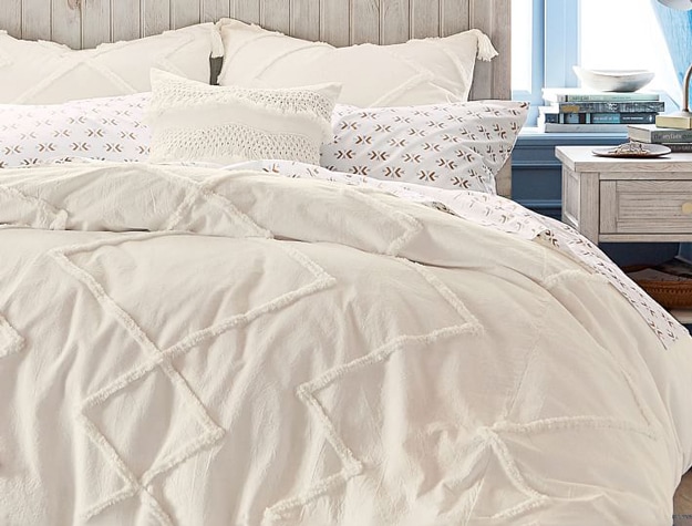 Ivory Ashlyn Tufted Organic Duvet Cover styled with matching pillows and white sheets.