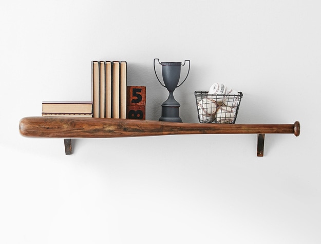 A baseball-shaped shelf holding baseballs, books and a trophy.