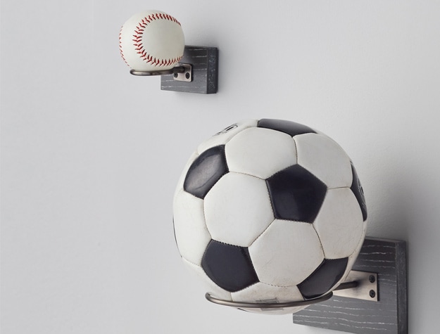 a soccer ball and baseball sitting on wooden ball holders