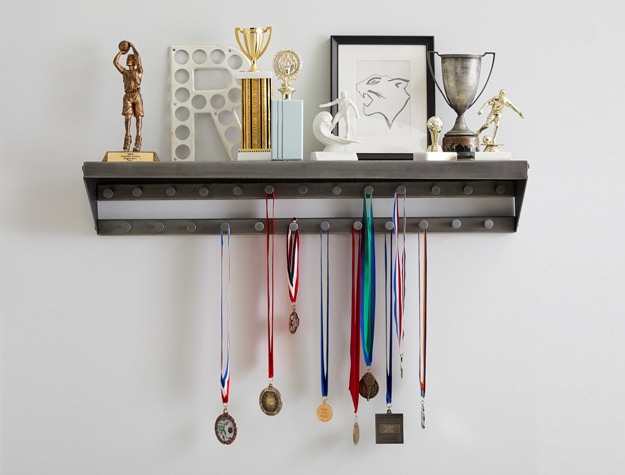 a shelf containing multiple trophies with medals hanging from the hooks below