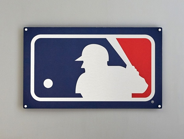 a metal sign showing the MLB logo displayed on a gray wall