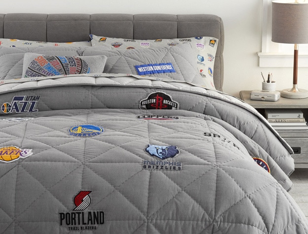 a bed with an NBA sham as well as NBA throw pillows and a quilt