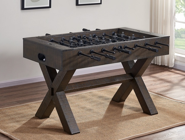 a foosball table sitting in an open room in front of two paintings