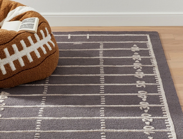 a rug resembling a football field sitting under a football bean bag