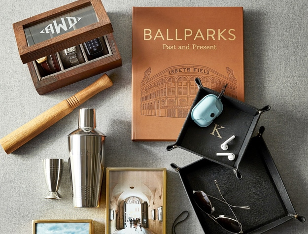 a book about baseball ballparks laying amongst photos, a cocktail shaker and other items.