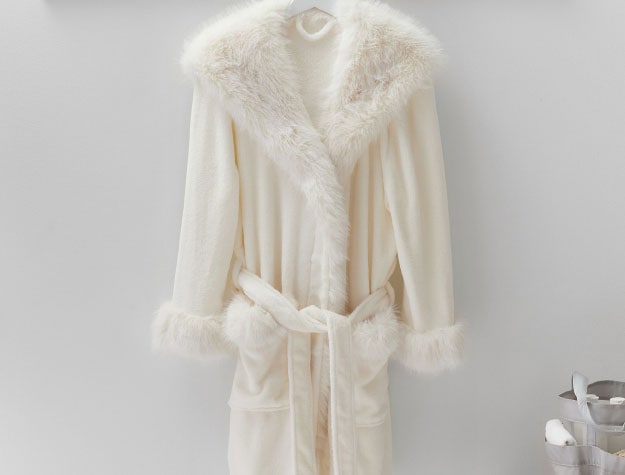 White feathery robe hanging up on a clothes rack.
