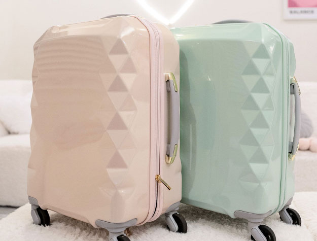 Two pieces of roller bag luggage, one pink and one green.
