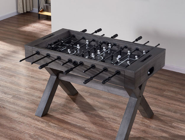 A wooden foosball table on top of a wooden floor.
