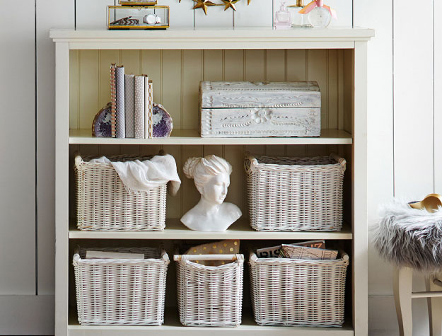 A medium-sized bookcase with books and baskets in the shelves.