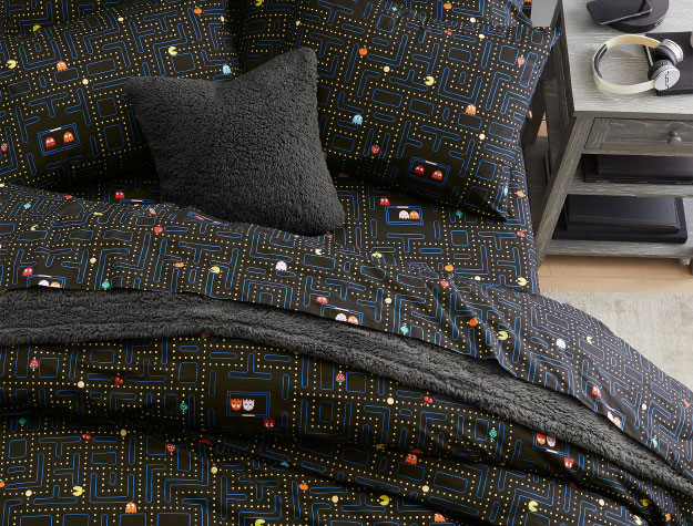 A set of PAC-MAN glow-in-the-dark sheets on a neatly-made bed.
