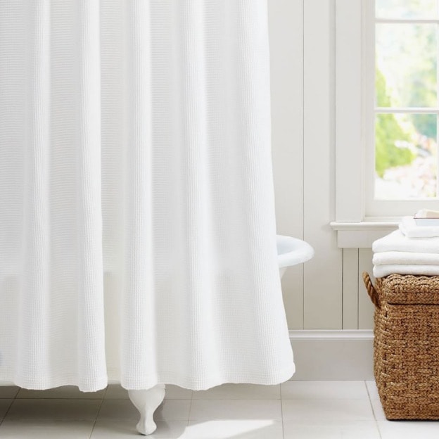 White shower curtain hanging above bathtub.