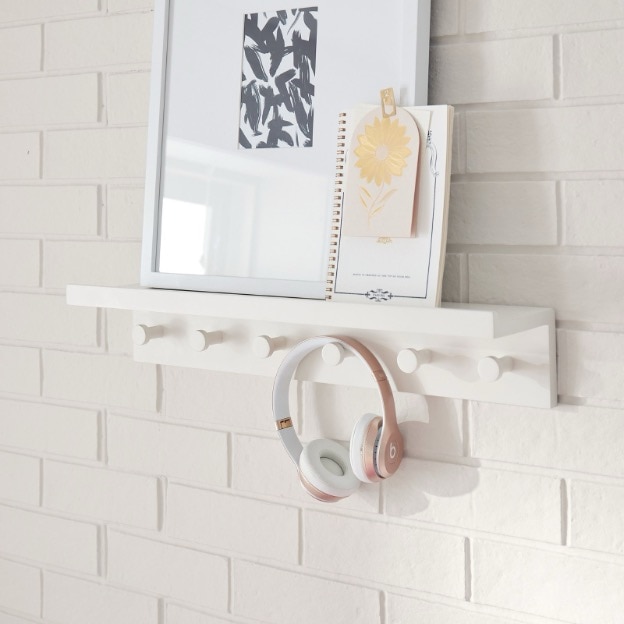 Wall decor including a pair of headphones hanging from a wall hook and a picture frame.