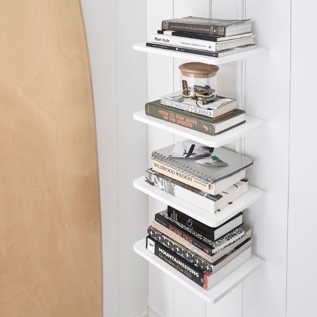 white 5-tier wall shelf holding books and knick knacks.