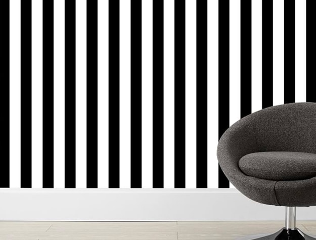 gray chair in front of black and white striped wallpaper