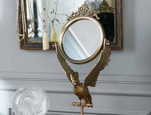 A mirror incorporating a phoenix into its design stands on a night table.