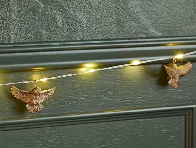 String lights featuring golden Hedwig accents hang across a wall.