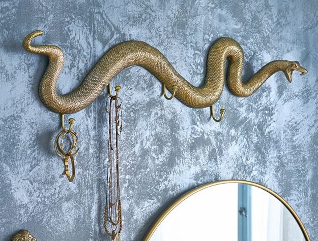 A brass wall hook shaped like Harry Potter’s Nagini hangs in a room.