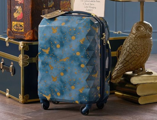 This carry-on roller suitcase features golden owls flying through the night sky.