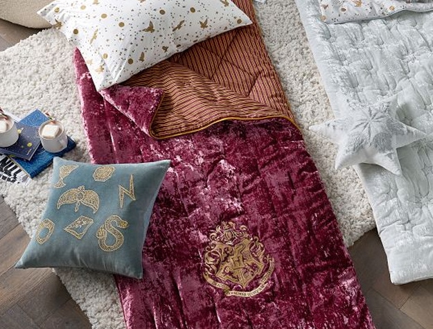 A burgundy velvet sleeping bag is styled with Harry Potter-inspired pillows.