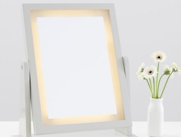 Desk mirror beside flowers in vase