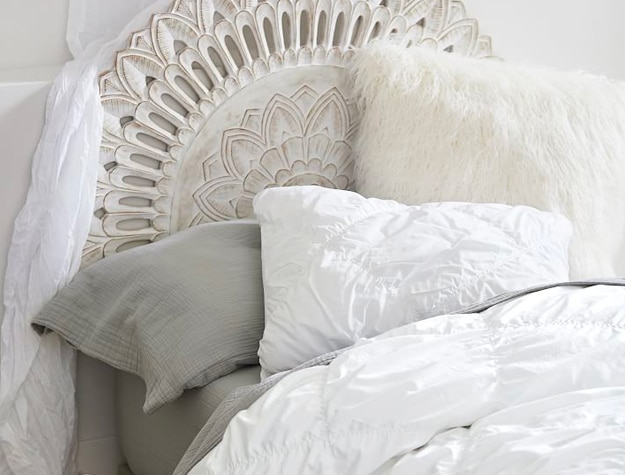 Carved wood mandala headboard behind bed