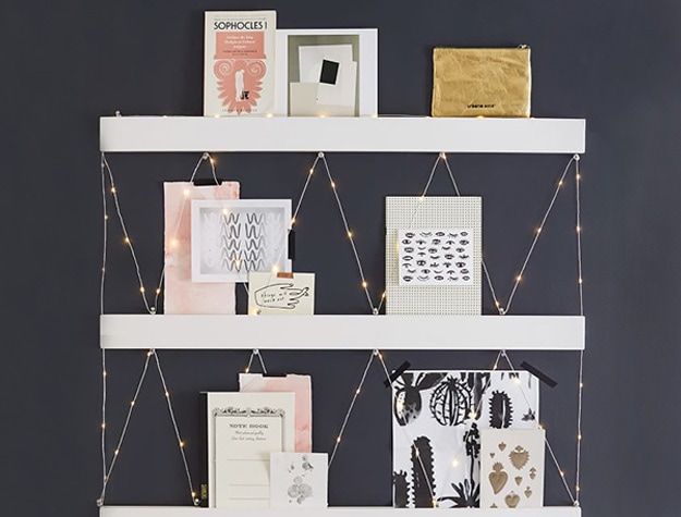 No nails photo rail hanging on wall with cards displayed.