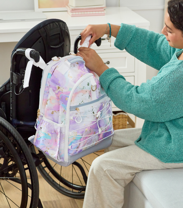 The third photo shows a close-up of a Pottery Barn Teen Gear-Up Adaptive Backpack in Storm print affixed to the handle of an assistive device.