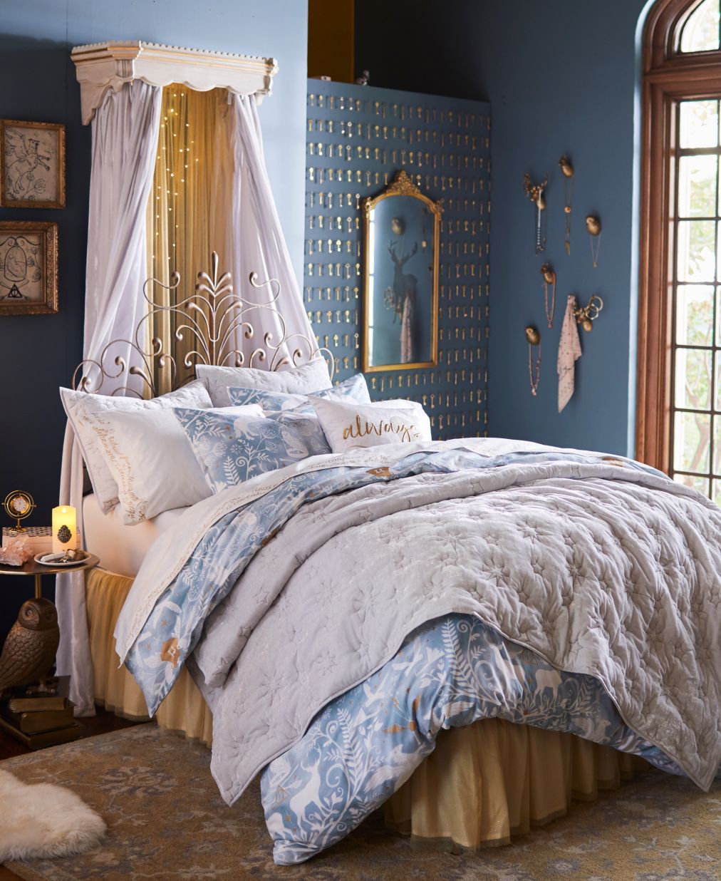 Harry Potter sample designed room. Shows a blue with gold themed accent bedroom with a bed with plush bedding, matching the color palette of the room. The gold accents around the room include Harry Potter themed items such as teh Golden Snitch, and a gold foiled image of a stag, which is Harry's patronus spell's form.