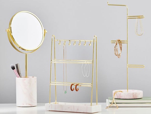 Gold jewelry organizers and mirror on vanity