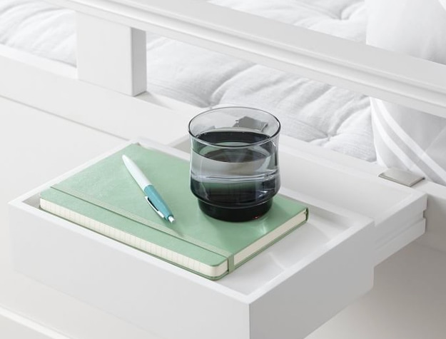 White bedside drawer with notebook and cup