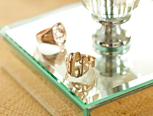 Two monogrammed rings on mirrored base