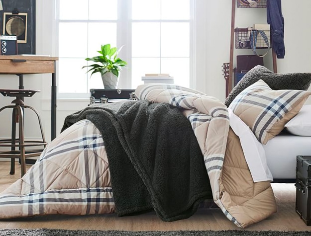 Black sherpa throw on bed with plaid comforter