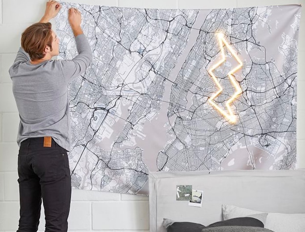 Teen boy putting up tapestry of Manhattan map