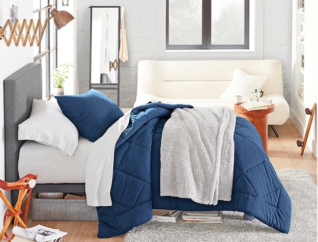 Bed with blue duvet and gray throw blanket