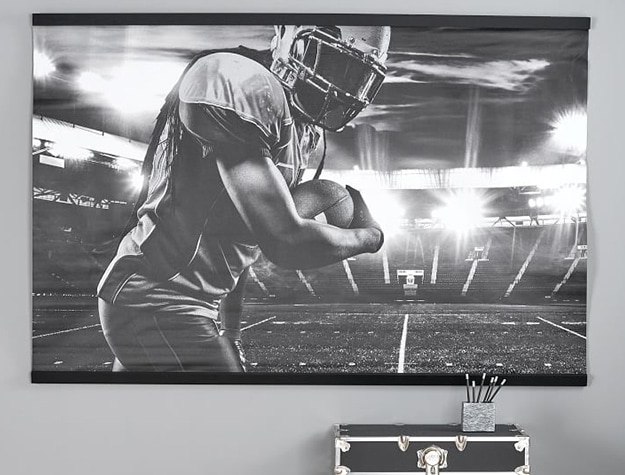 Black and white football wall mural in bedroom with black chest below it