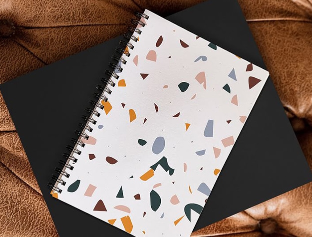 Speckled-pattern spiral notebook on couch
