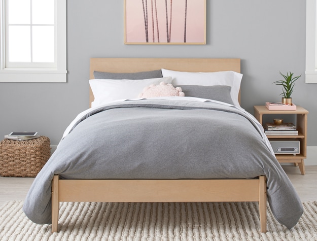 Slender wooden bed with gray bedding