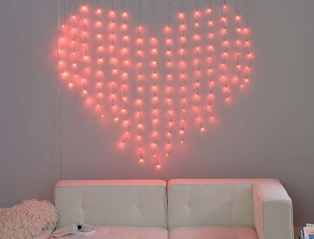 Red heart-shaped color changing waterfall string lights hanging on a wall over a sofa