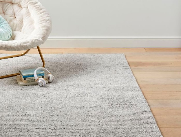 A lounge chair and books on a Tufted Grid Performance Rug.